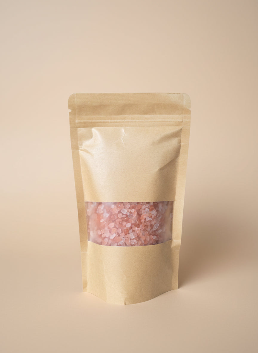 Kraft paper packaging with a clear window showing pink contents on a white surface.